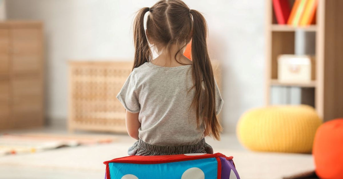 Flicka sitter ensam i ett lekrum – symboliserar autism hos flickor och deras unika sätt att uppleva världen.