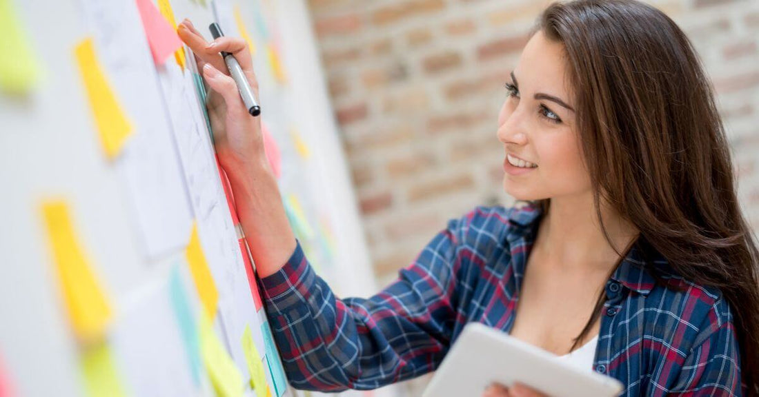 Kvinna planerar sin dag med post-it-lappar och surfplatta – en visuell strategi för bättre vardagsstruktur vid NPF.