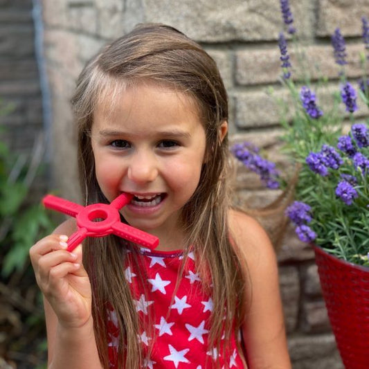 Flicka tuggar på rött Tetra-Bite Fidget för NPF, visar trygg oral stimulans.