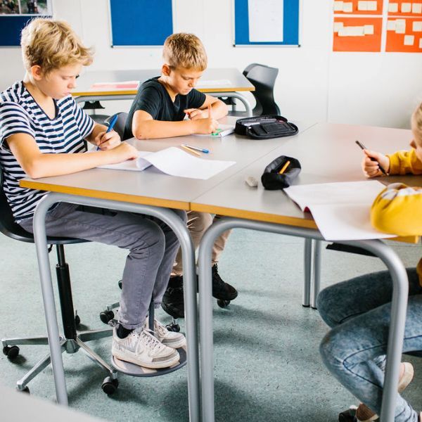 Klassrum med elever som använder SWNX One-fotgungor under bordet för ökad fokus och rörelsefrihet.
