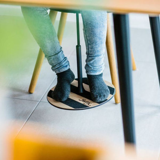 Barns fötter i rörelse på SWNX Original fotgunga under ett matbord.