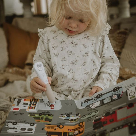 Barn som använder Readioo läspenna för att utforska boken Mina första 100 ord: Fordon med bilder på olika fordon.