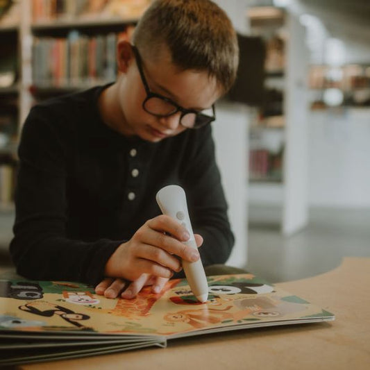 Pojke använder Readioo läspenna med boken "Mina första 100 ord: Djur".
