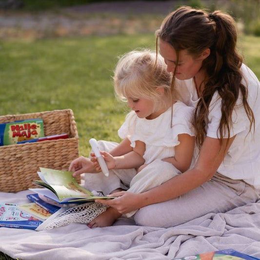 Vuxen och barn läser interaktiv Readioo-bok tillsammans med läspenna, skärmfri och lugn lässtund.
