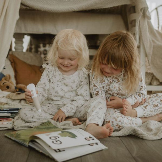 Två barn i pyjamas har lässtund tillsammans med Readioo-boken Bokstäver och läspennan.