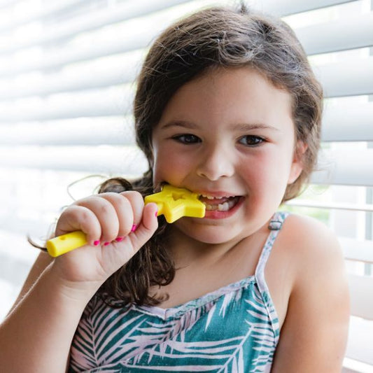 Flicka tuggar på Trollspö i rosa, lång design med stjärnände.