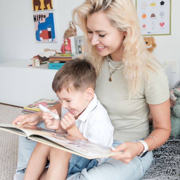 Mamma och barn läser en bok tillsammans och använder Readioo läspenna.