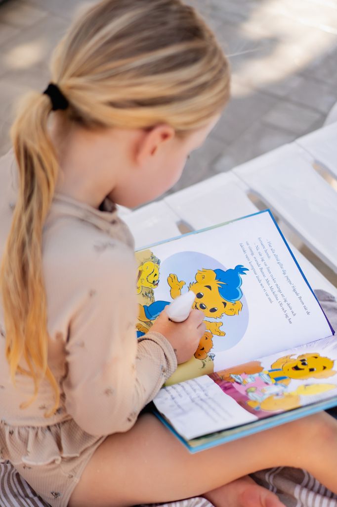 Barn läser Bamse-bok med Readioo Läspenna och följer berättelsen interaktivt.