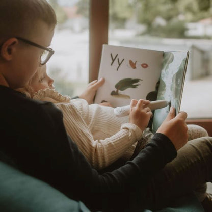 Två barn läser i Readioo-boken Bokstäver och använder läspennan för att lyssna på bokstavsljud.