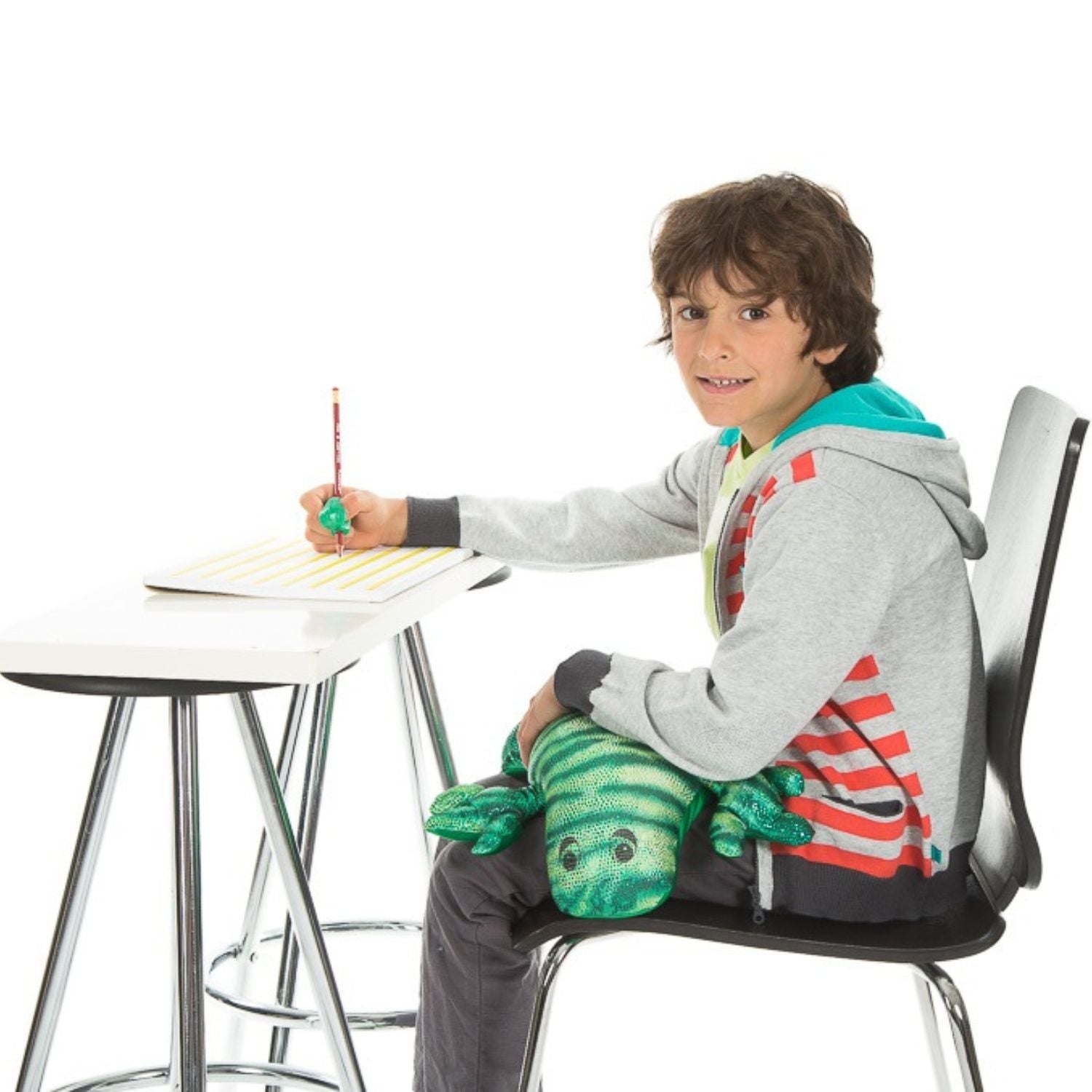 Barn skriver med grön Manimo Tyngdödla i knät, tyngddjur för fokus, koncentration och sensoriskt stöd.