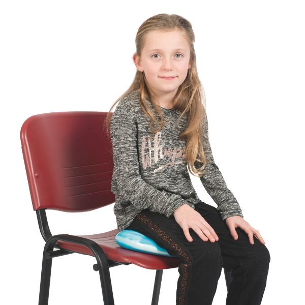 Barn som sitter på blå Bitty Bottom sittkudde, hjälpmedel för balans och koncentration