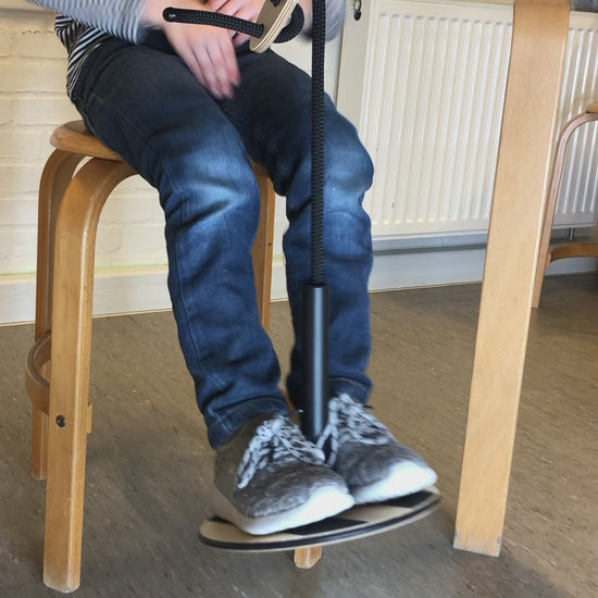 Barn använder SWNX Mini Original fotgunga under bordet medan han skriver i sin bok, för bättre fokus och lugn.