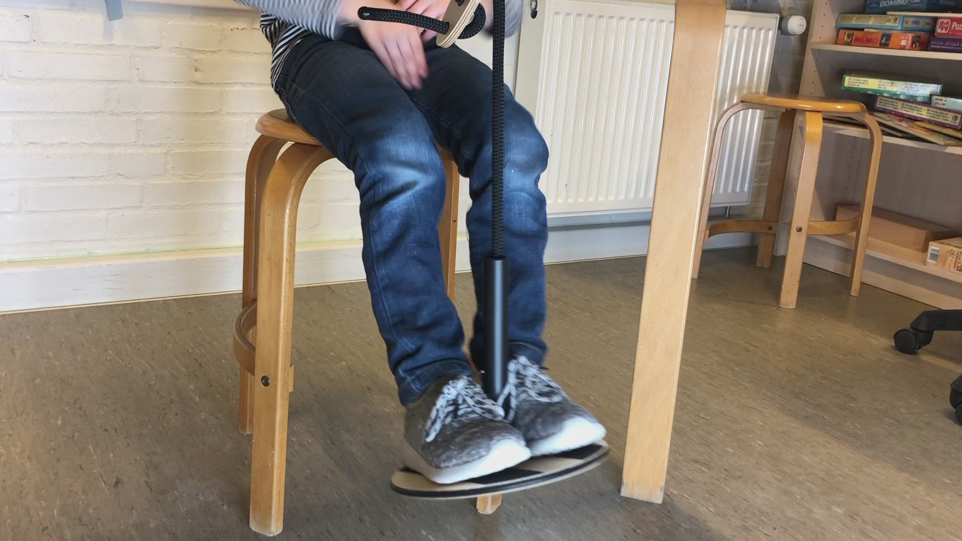 Barn använder SWNX Mini Original fotgunga under bordet medan han skriver i sin bok, för bättre fokus och lugn.