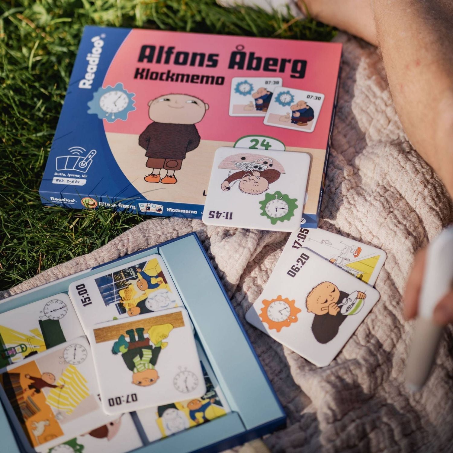Readioo Alfons Åberg Klockmemo utomhus med brickor som visar klockslag både analogt och digitalt, som 07:30 och 11:45.