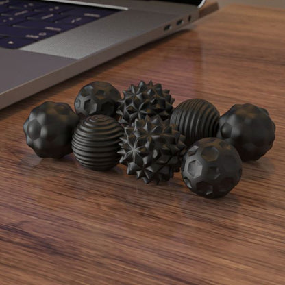 Svarta sensoriska fidgetkulor på skrivbord vid laptop. 