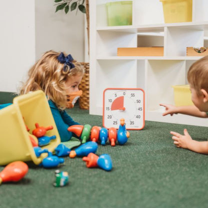 Barn leker på golvet med färgglada leksaker och en röd Time Timer Medium som hjälper till att hålla fokus.