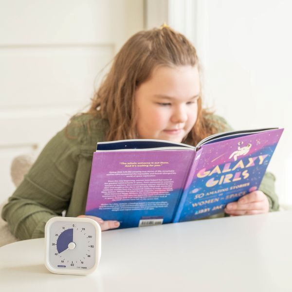 Barn läser bok med Time Timer MOD 120 min bredvid som stöd för tydlig tidsuppfattning och lugn