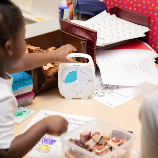 Barn använder Time Timer PLUS 20 min under skolaktivitet vid bord.